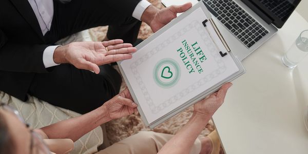 Advisor showing a life insurance policy to a client during a meeting at home.