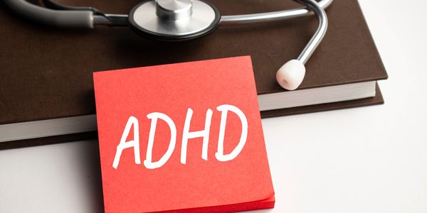 Sticky note with ADHD near a stethoscope on a book.