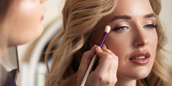 Woman getting makeup applied with brush.