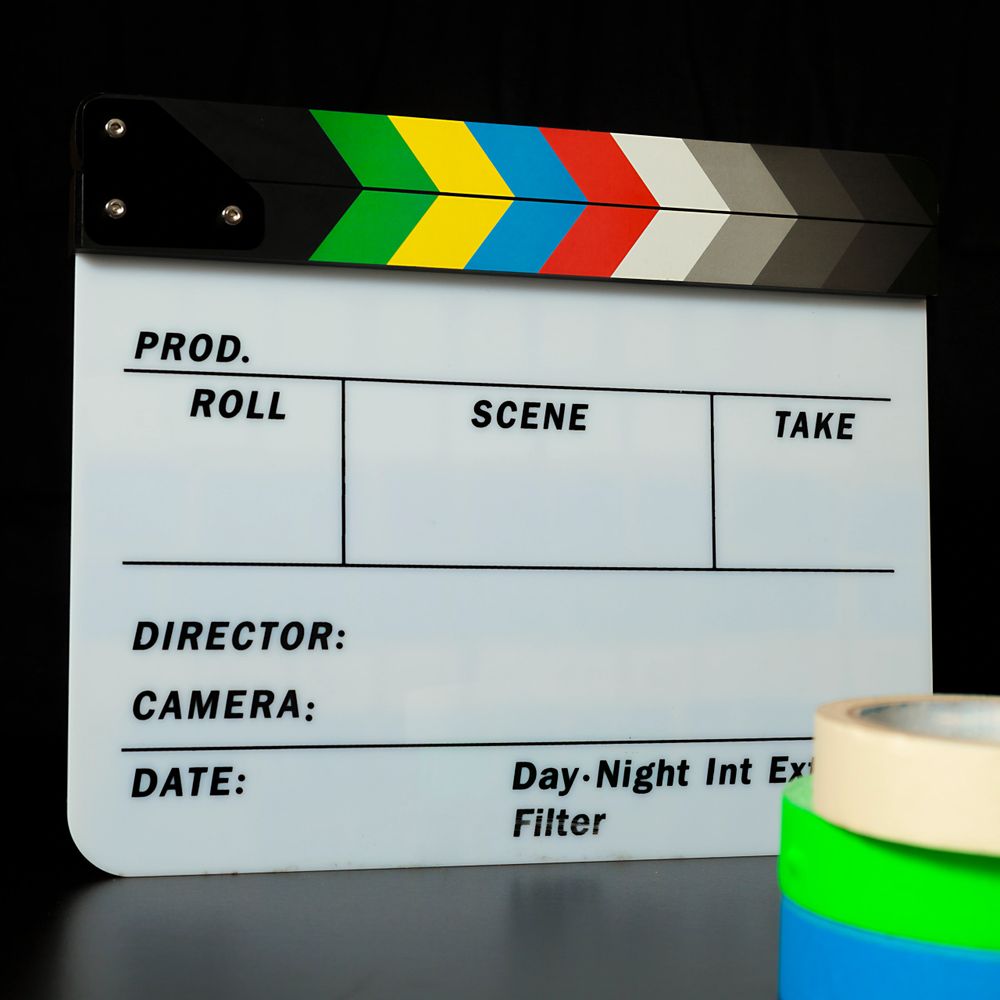 A colorful film clapperboard with blank sections for production details and rolls of tape.