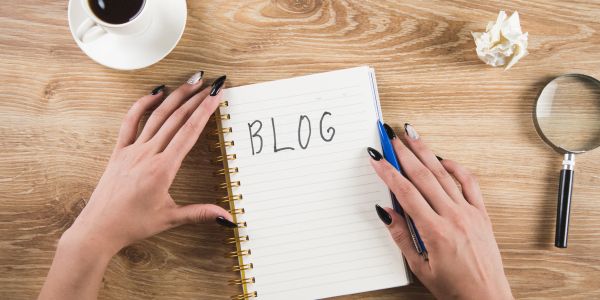 Hands holding a notebook with 'BLOG' written on it.
