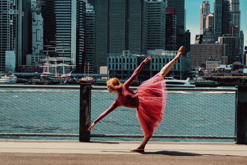 young gorgeous ballerina dancing on street, downtown Brooklyn, New York City financial district cityscape