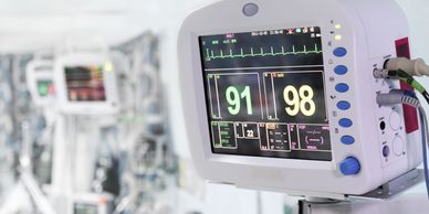 Close-up of a medical monitor displaying vital signs in a hospital setting.