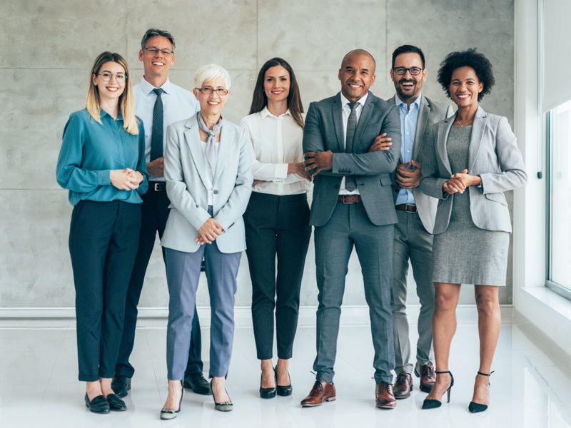Multi-ethnic group of business persons standing in modern office and looking at camera