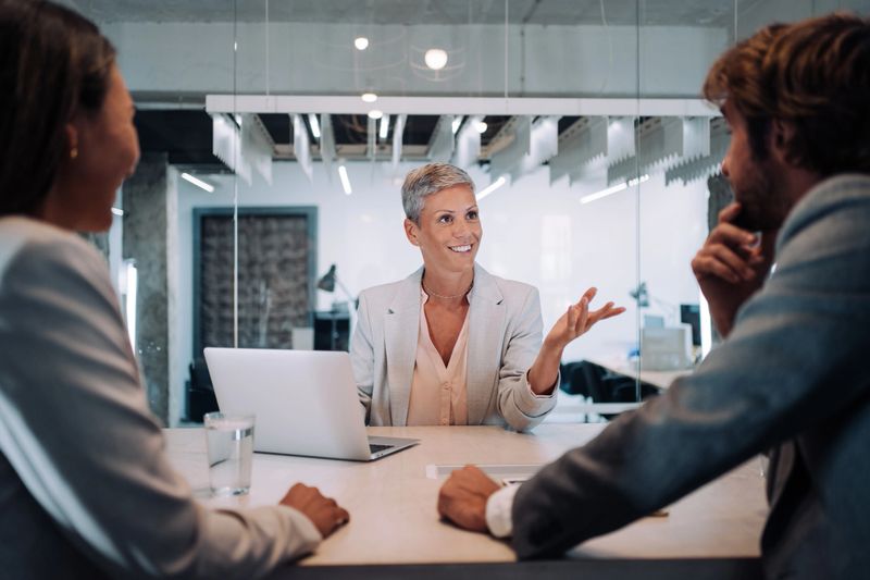 Shot of young couple having a consultation with a financial advisor in the office. Group of business persons in business meeting. Three entrepreneurs on meeting in board room. Corporate business team on meeting in modern office. Female manager discussing new project with her colleagues. Company owner on a meeting with two of her employees in the office.