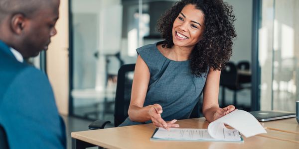 A woman smiling and discussing documents with a man in a professional office setting.