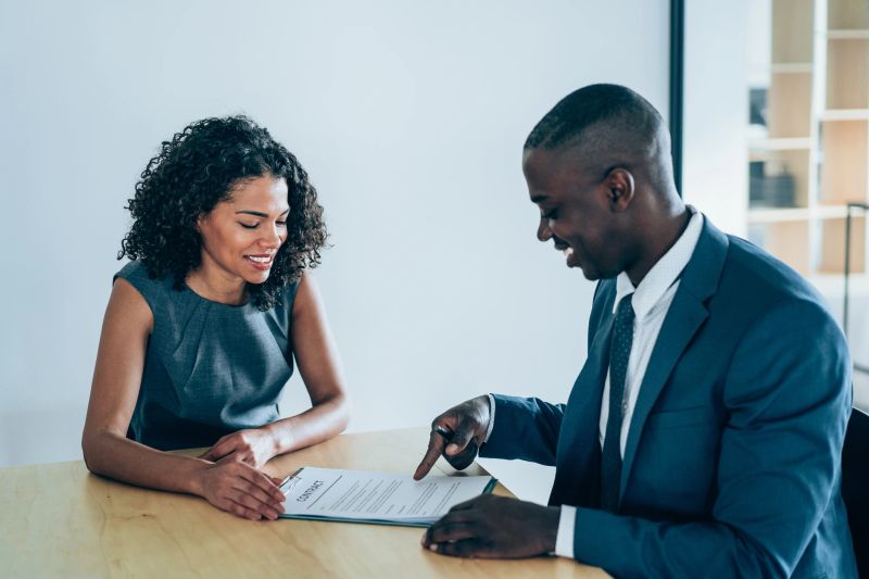 Shot of two business persons filling in paperwork in the office. Businessman and businesswoman signing a document in board room.