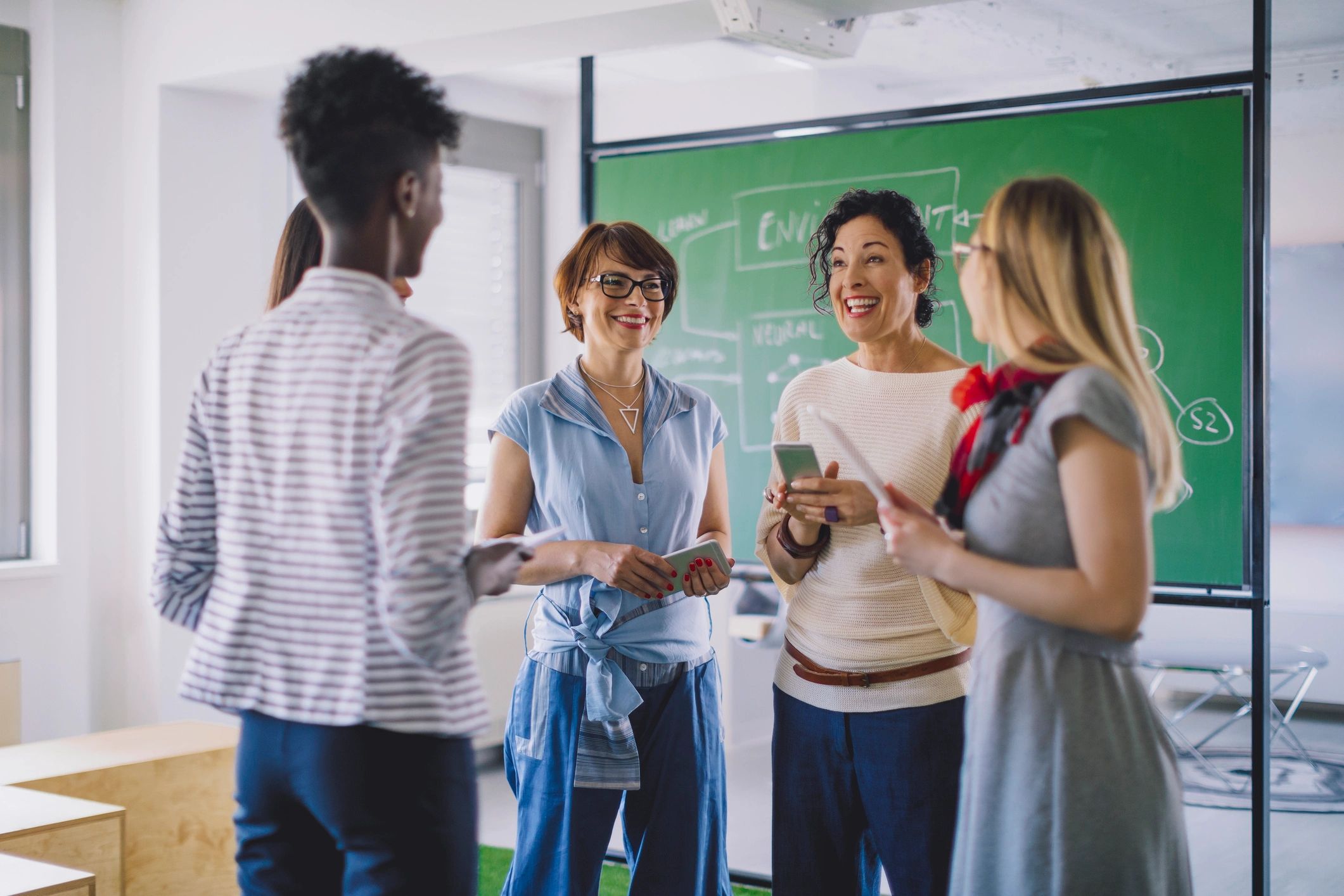 Group of people chatting in front of a chalkboard.
