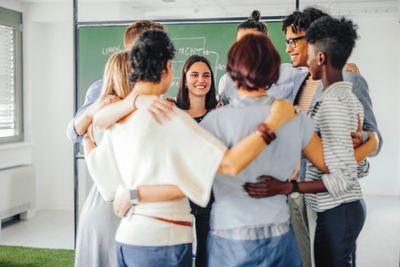 A diverse group of people standing in a circle, smiling and hugging.