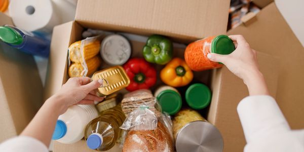 Person packing a box with groceries and canned goods.