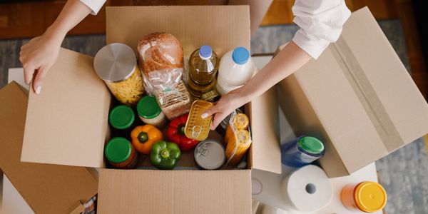 a range of produce including drinks, vegetables and other food goods in a cardboard box