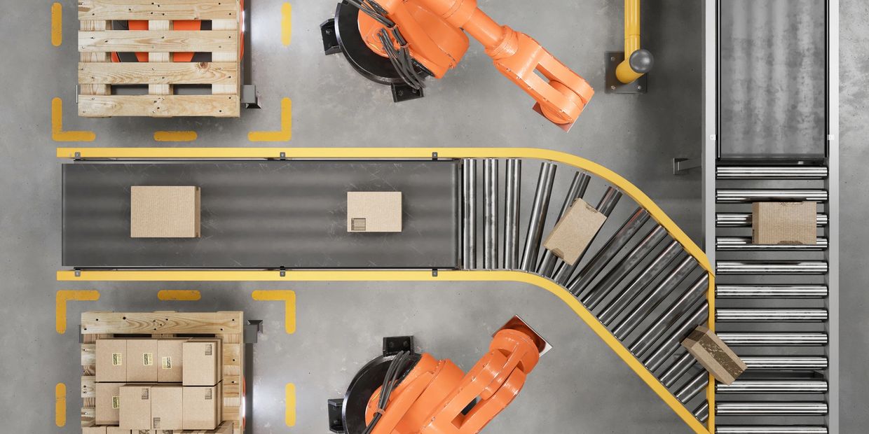 Overhead view of robotic arms sorting cardboard boxes on conveyor belts in a warehouse.
