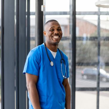 Smiling healthcare worker in blue scrubs with stethoscope.