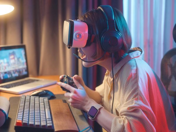 Gamer wearing VR headset and headphones, holding a controller intensely.