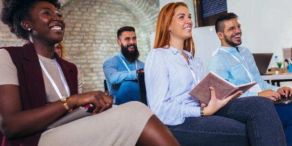 Diverse group attending a seminar, smiling and engaged.