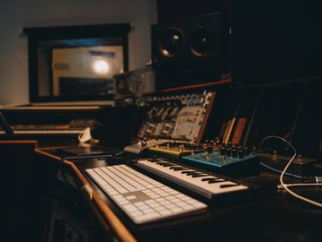 A dimly lit music studio with a keyboard, mixer, and speakers.