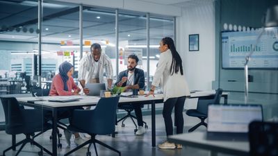 Four colleagues collaborate around a table in a modern office.