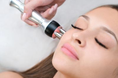 Woman receiving a facial treatment with a modern skincare device.