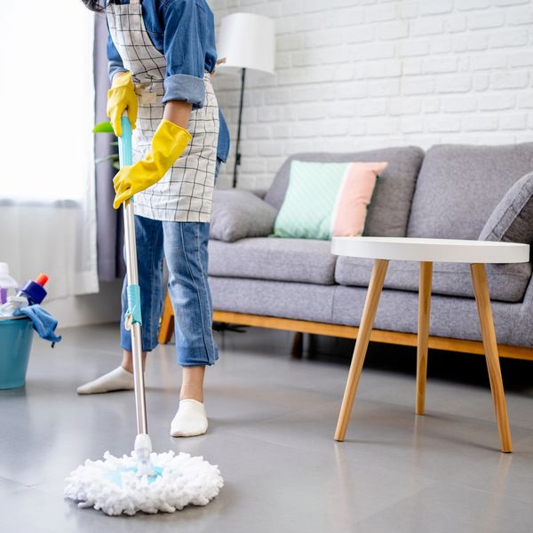 Person mopping floor in a clean, modern living room.