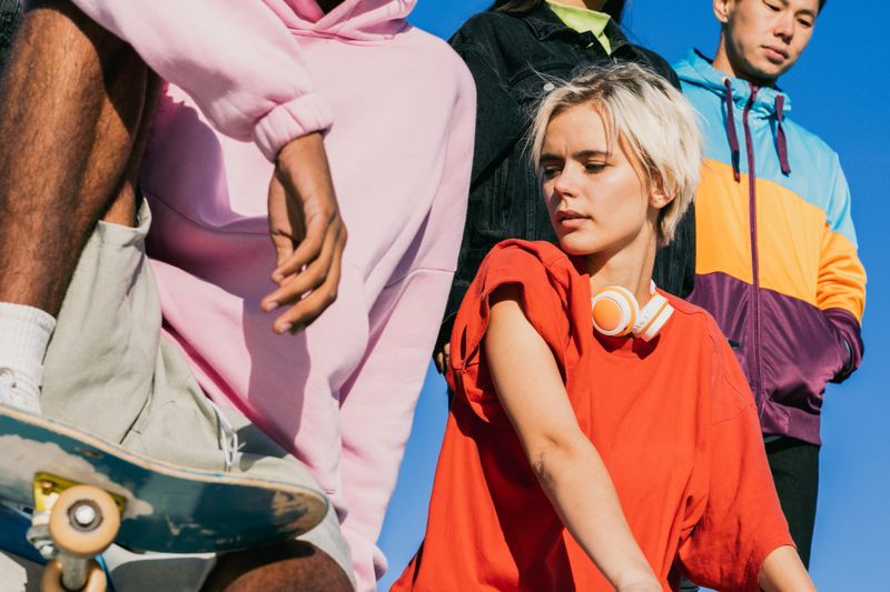 Multicultural group of young friends bonding outdoors and having fun - Stylish cool teens gathering at urban skate park