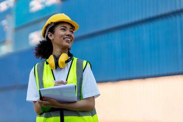 Smiling construction worker in safety gear holding clipboard.