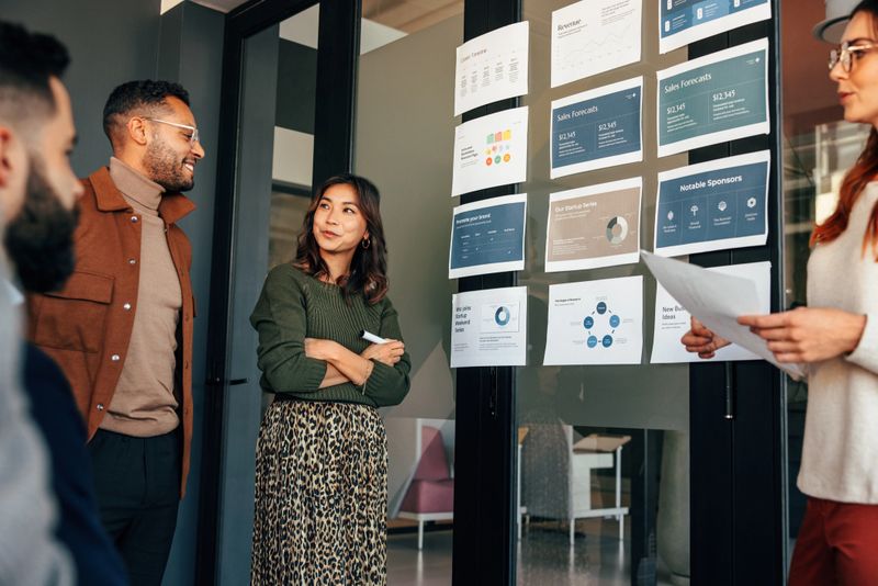 Team of businesspeople analyzing some reports in a boardroom. Group of multicultural businesspeople having a meeting in a modern office. Diverse entrepreneurs collaborating on a project.