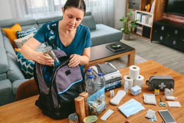 Woman packing emergency supplies into a backpack.