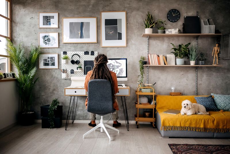 Young graphic designer working from his home office while his dog is laying near him