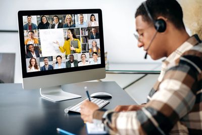 A student attends an online class with multiple participants on screen.