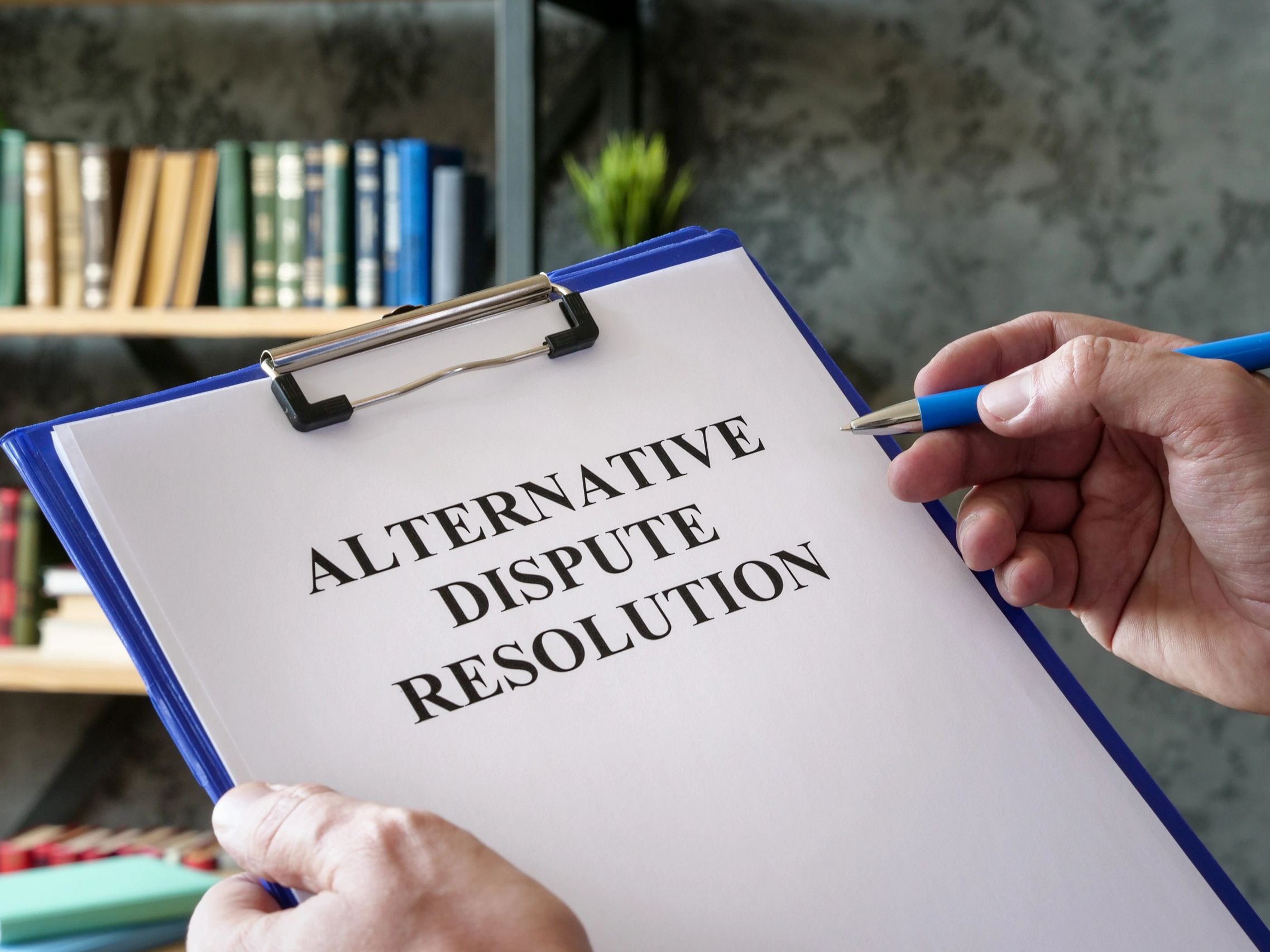 A lawyer holding a clipboard and pen, looking at a note that says "ALTERNATIVE DISPUTE RESOLUTION".