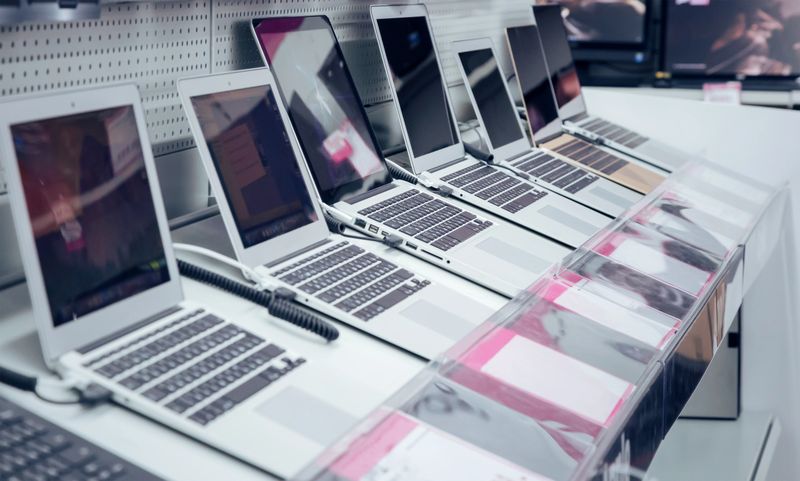 Various types of portable computers are presented for sale in the shop window.