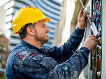 Elektriker bei der Arbeit mit gelbem Helm.