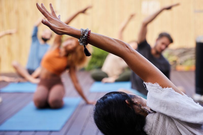 Rear view of a yoga teacher leading her students through poses during an outdoor class together