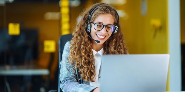 Woman with headset working on laptop in office.