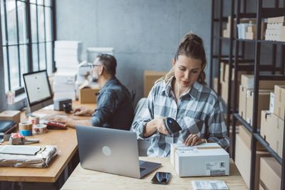Woman scanning package barcode at her desk.