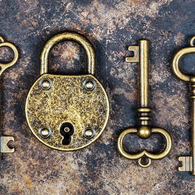 Antique brass padlock and keys on a textured surface.