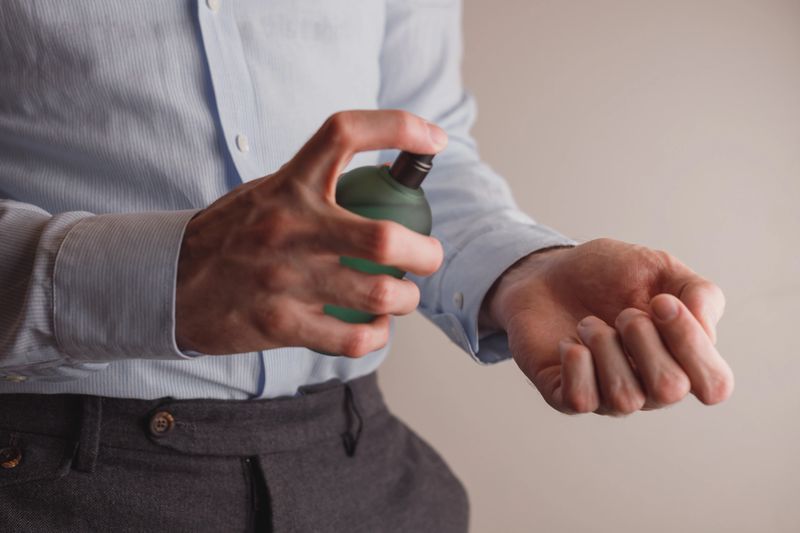 Man in formal wear holding perfume bottle, closeup. Space for text