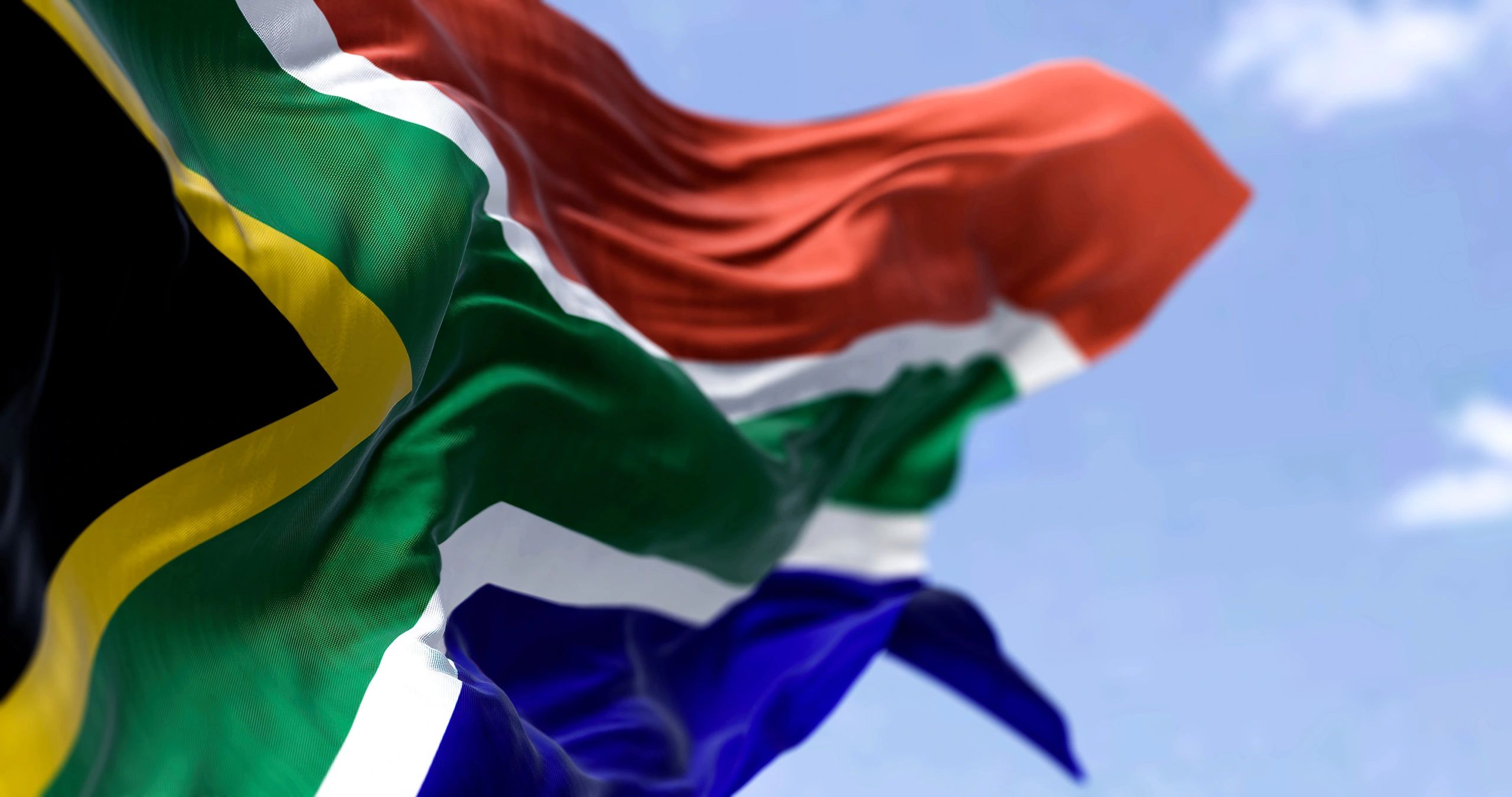The South African flag waving against a clear blue sky.