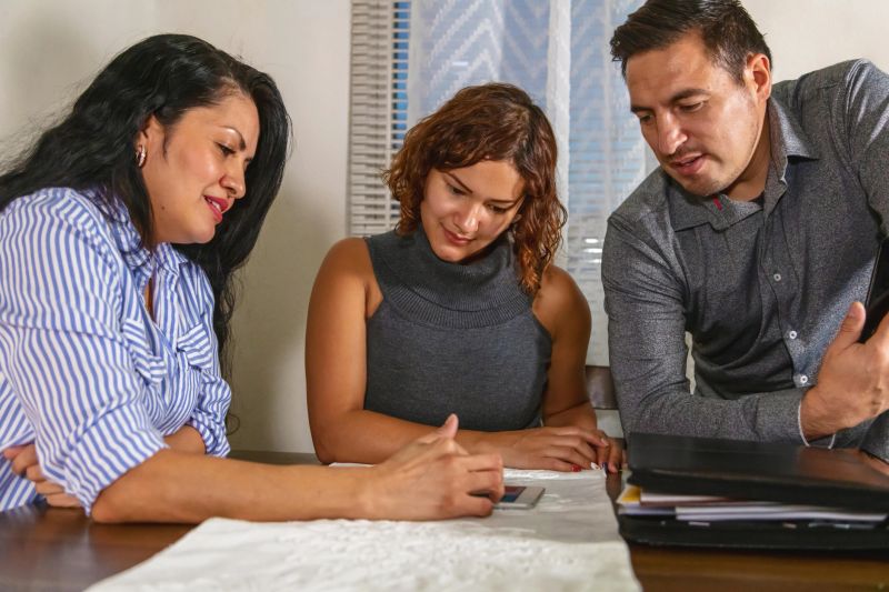 Multi-Generational Colombian Family in Home with Insurance Agent Discussing Life Insurance Policies as a Family Hispanic Photo Series (Shot with Canon 5DS 50.6mp photos professionally retouched - Lightroom / Photoshop - original size 5792 x 8688 downsampled as needed for clarity and select focus used for dramatic effect)