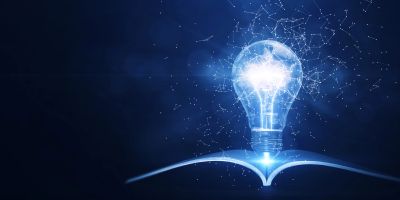 Glowing light bulb above an open book.