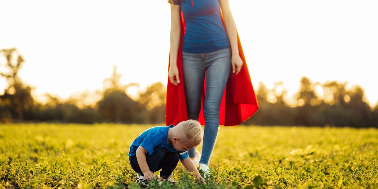 A child and his mother in a superman cape.
