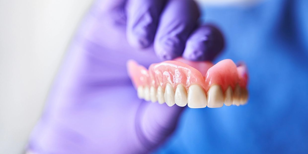 Gloved hand holding dentures.