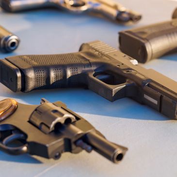Several handguns placed on a flat surface.