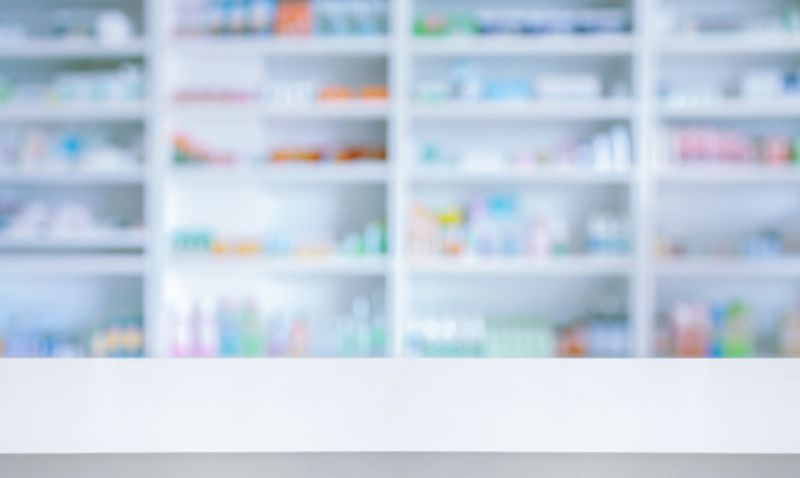 Empty white counter with pharmacy drugstore shelves blurred background
