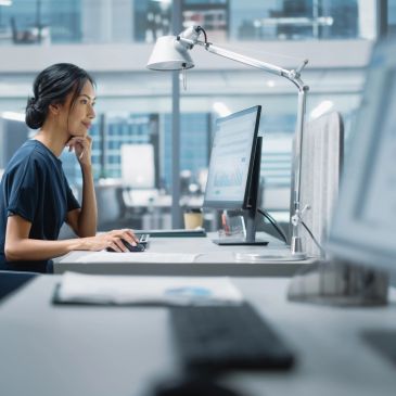 Mujer trabajando frente a una computadora en una oficina moderna.