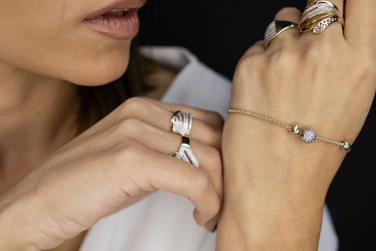 Close-up of a woman's hand wearing elegant gold and diamond rings and a delicate bracelet.