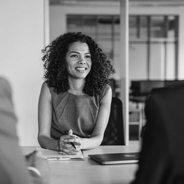 Woman confidently interviewing with two professionals in a modern office.