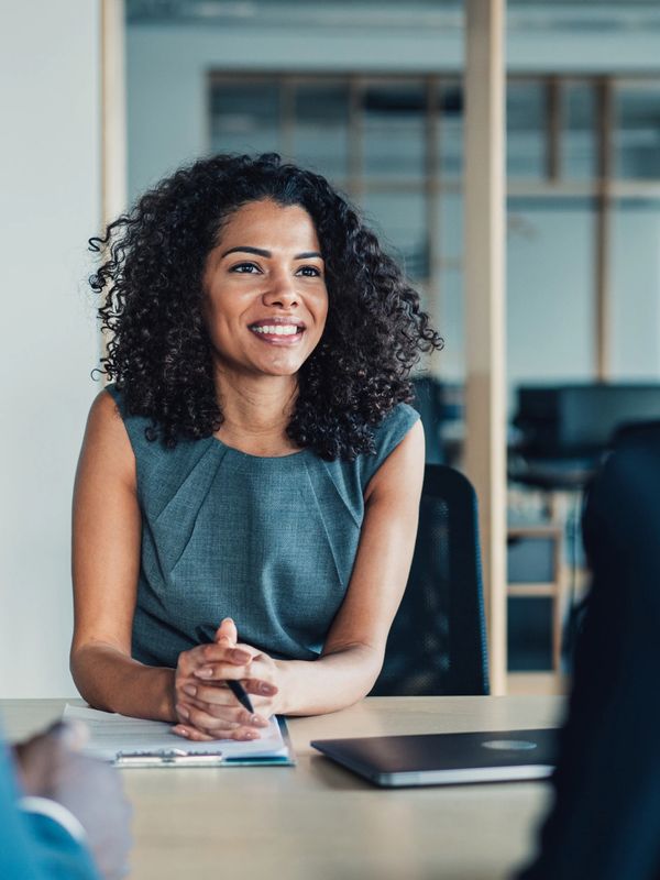 Smiling woman in a professional interview setting with two interviewers.