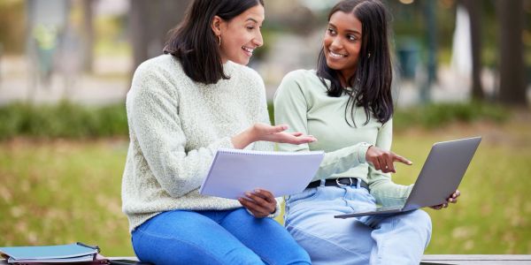 Two young women studying and discussing outdoors.