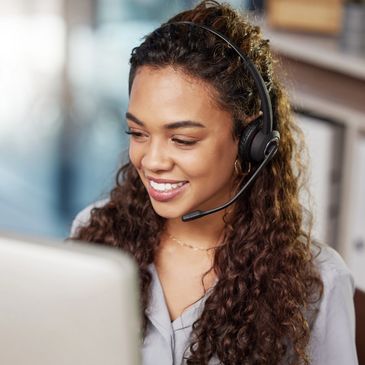Smiling woman with headset working at her computer.